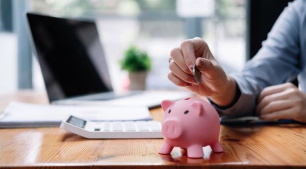 Woman putting coins into a piggy bank on her desk