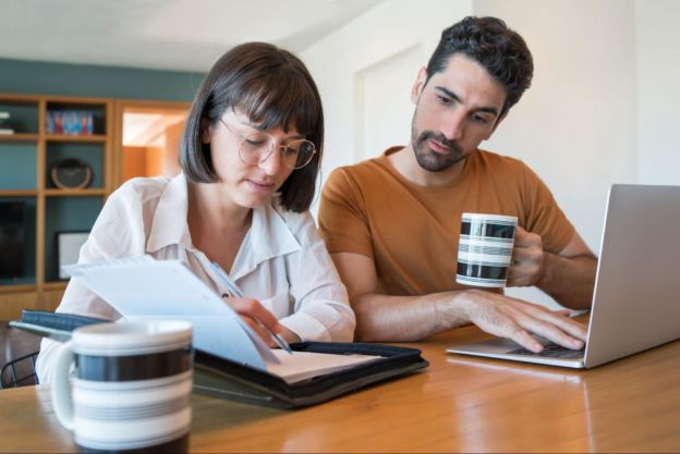Couple sitting together at a table looking at a planner together