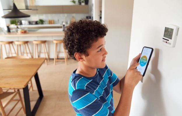 Kid adjusting a smart thermostat app on a smartphone